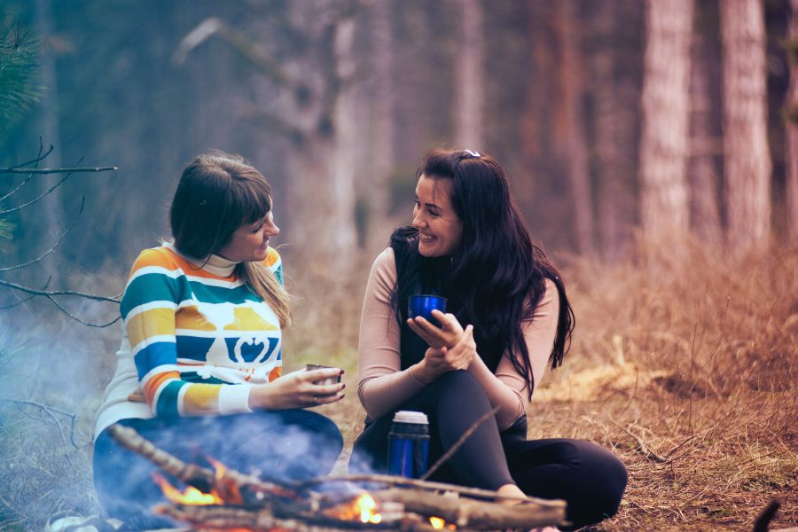 Girlfriends chatting sitting next to bonfire.