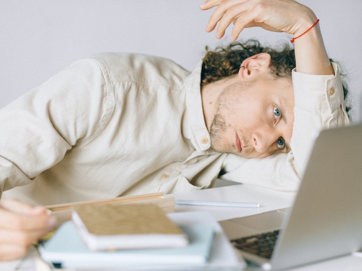 A man laying on a desk trying to make a decision